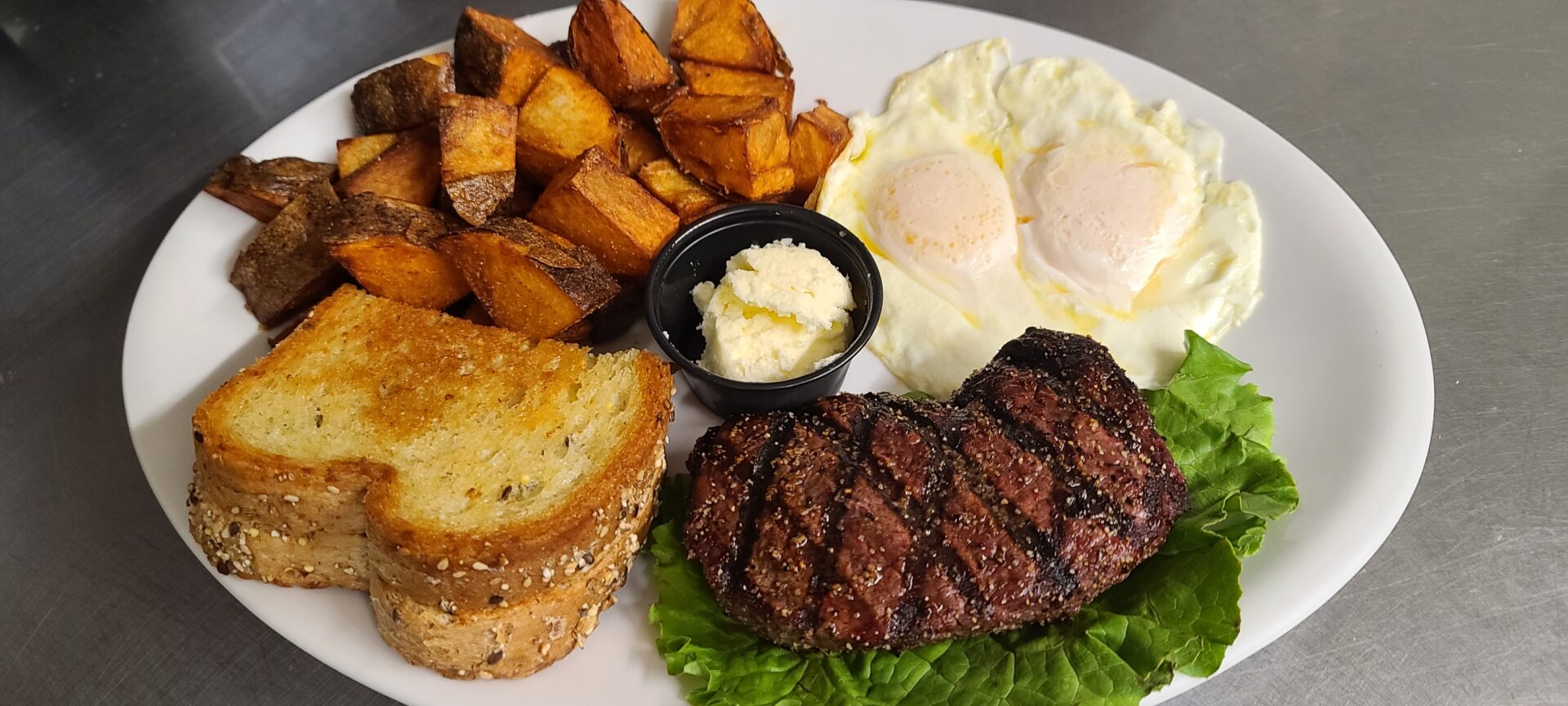 A plate of food with steak, potatoes and eggs.